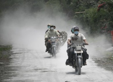 Motorcyclists ride along roads coated with volcanic ash from Mt Sinabung.