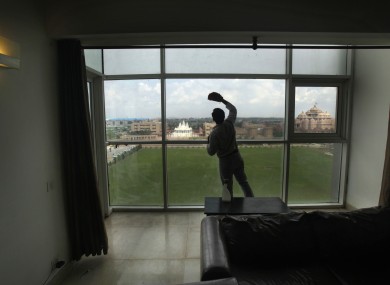 A worker cleans the window of a room in the athlete's village in New Delhi