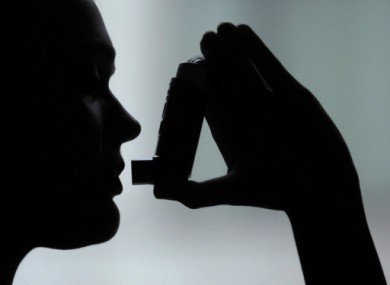 A woman prepares to take a puff from an inhaler.