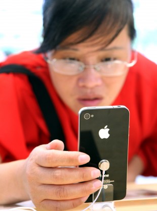 A Chinese buyer examines a display iPhone 4 in Shanghai. The white edition of the handset has been delayed yet again.