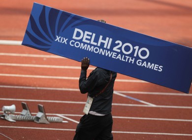 A worker carries a Delhi 2010 signboard across the track in preparations for the track and field event of the Commonwealth Games at the Jawaharlal Nehru Stadium