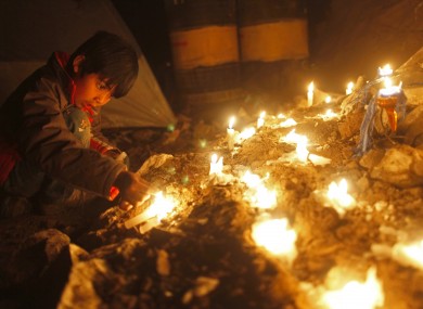 A relative of one of the 33 miners trapped lights a candle during a vigil outside the San Jose mine in Copiapo last night.