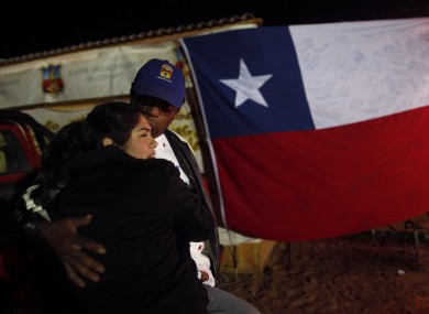 Ezequiel Rivera hugs his daughter at the camp were relatives of a trapped miners wait for news of the rescue effort