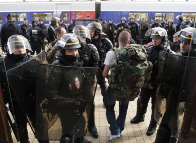 French riot police officers secure the area at the Bordeaux train station, southwestern France, as a passenger arrive during a demonstration against pension reforms, on 22 October, 2010.