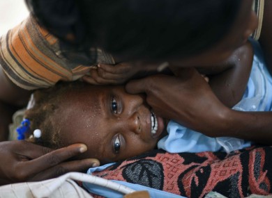 A mother comforts her crying daughter, who displays symptoms of cholera, at the hospital in Grande-Saline, Haiti.