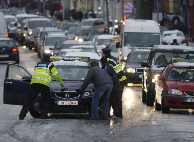 Gardai help motorists deal with icy roads along North Strand during Rush Hour in central Dublin yesterday.
