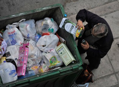 A man empties out the remains of an olive oil container before dumping it in the Greek city of Thessaloniki. S&P now deems Greek government bonds firmly in 'junk' territory.