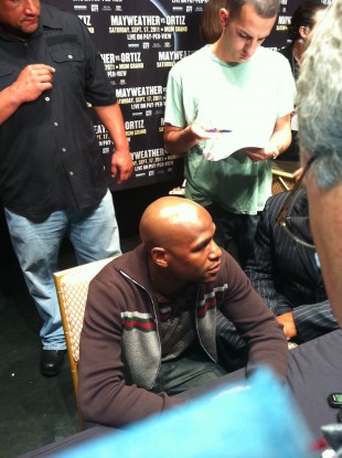 Money Mayweather at the top table, surrounded by journalists.