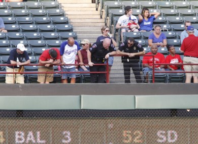 Police and fans look over the railing where a fan fell from the stands during the second inning of a baseball game between the Texas Rangers and the Oakland Athletics.
