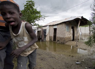 A boy looks at the camera as he walks past a partially flooded house on the outskirts of L'Estere, Haiti.