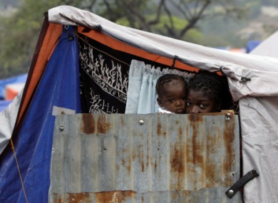 A woman and child peer from their emergency housing at the Petionville Golf Club in Haiti, two months after the 2010 quake.