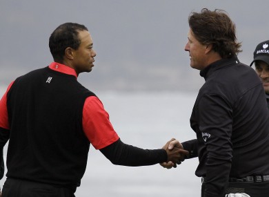 Tiger Woods, left, shakes hands with Phil MIckelson on the 18th green.