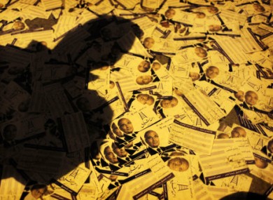 An Egyptian supporter walks on scattered electoral flyers with pictures of presidential runoff candidate Ahmed Shafiq in front of his ransacked campaign headquarters.