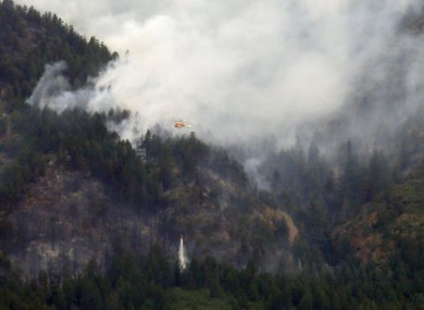 A water dropping helicopter makes a run over a plume of smoke rises form the Waldo Canyon wildfire west of Colorado Springs.