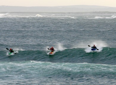 Kayakers ride a large wave at the popular surf beach of Spanish Point, County Clare - now reopen for business.