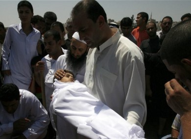 A relative holds the body of 6-year-old Syrian boy Bilal El-Lababidi during his funeral in Ramtha, Jordan, Friday, July 27, 2012.