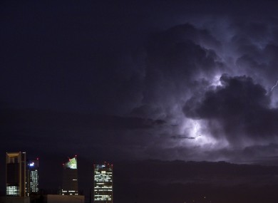 An electrical storm lights up the night sky behind the business district in Madrid, Spain, Wednesday, Oct. 10, 2012.