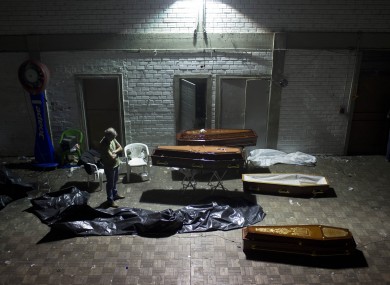 A man stands around coffins containing the remains of victims in Brazil.