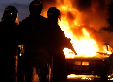 Riot police stand next to a burned out car after Loyalist protesters attacked police lines, in east Belfast.