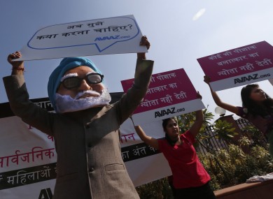 A man wearing a mask of Indian Prime Minister Manmohan Singh, left, participates in a protest along with women outside the court in New Delhi, India