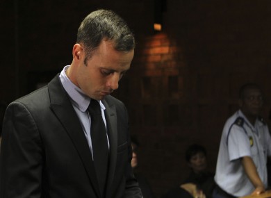 Olympic athlete Oscar Pistorius stands inside the court as a police officer looks on.