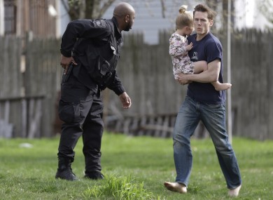 A police officer evacuates a shoeless man holding a child in Watertown, Massachusetts.