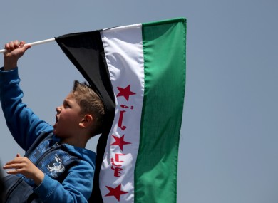 A boy waves the Syrian revolutionary flag as protesters chant anti-Bashar Assad slogans and pro-Jabhat al-Nusra and Free Syrian Army slogans, in front of the Syrian embassy, in Amman, Jordan, last Friday.