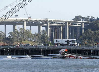 The Artemis Racing AC72 catamaran, an America's Cup entry from Sweden, lies capsized near the Oakland-San Francisco Bay Bridge.