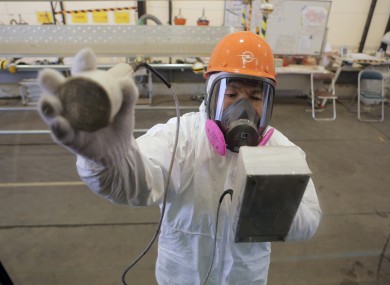 A worker checks radiation level over a press bus at the crippled Fukushima Dai-ichi Nuclear power plant.
