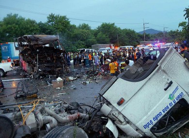 The charred wreckage of a double-decker passenger bus, top left, sits in the middle of a highway after a collision with a truck, foreground, in Saraburi province, northeast of Bangkok.
