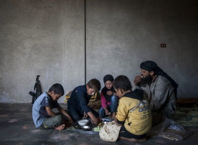Ahmed al-Fikri sits with his sons and daughter, among them 12-year-old Abdo al-Fikri, second left, to eat lunch at their family house in Madaya village after school in the Idlib province countryside of Syria.