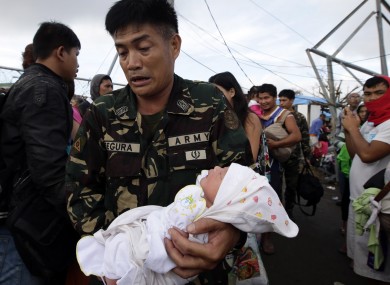 A soldier carries one-day-old baby Ian Daniel Honrado to a waiting military transport plane at Tacloban city, central Philippines.