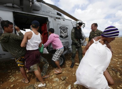 Trapped residents unload relief supplies from a U.S. Navy helicopter for villagers isolated by last week's super typhoon Haiyan.