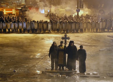 Orthodox priests pray as they stand between pro-European Union activists and police lines in central Kiev