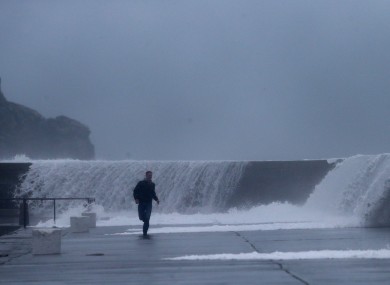 A man runs from waves crashing onto the East pier in Howth yesterday