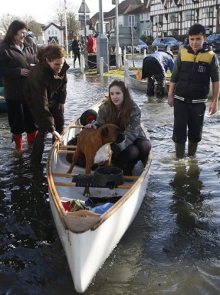 A girl sits with her dog in a boat on a flooded street, in Datchet, England.