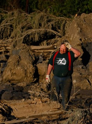 Jason Anderson searches through rubble for bodies.