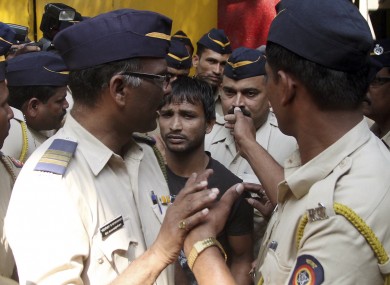 Police officials escort one of the four convicts in the case to court