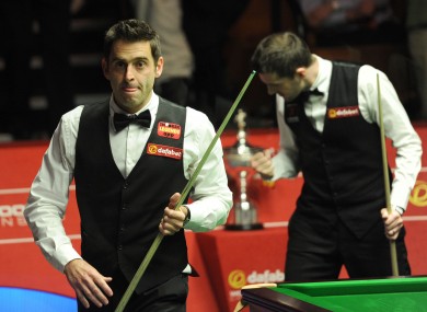 Ronnie O'Sullivan leaves the arena as Mark Selby celebrates winning the final frame of the afternoon session.