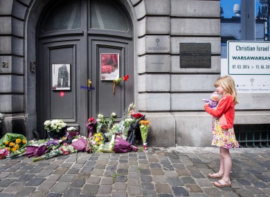 A girl stands next to flowers at the Jewish Museum in Brussels after three people were killed in a shooting.