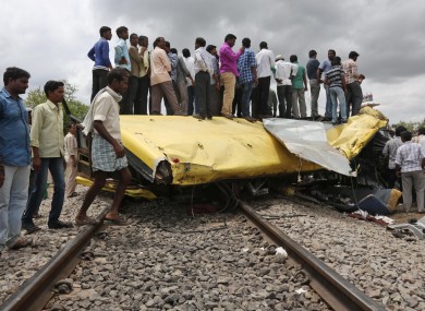 Locals and relatives of victims stand on the schoolbus crushed by a train in the Medak district of India.