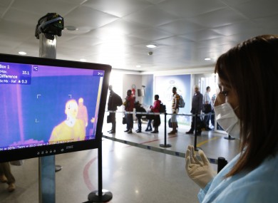 Moroccan health screening team dressed in protective gear uses a thermometer on passengers at the arrivals hall of the Mohammed V airport in Casablanca