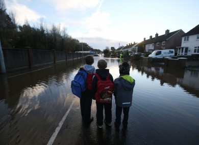 Children look at flood water on Nutgrove Avenue in Dublin on their way to school on Friday.