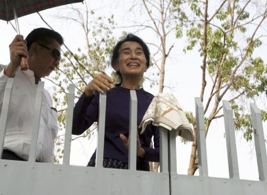 Aung San Suu Kyi smiles over the gates of her residence where she was under house arrest.