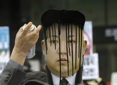 A South Koran protester spray paints a picture of Kim Jong Un