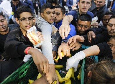 Men grab for food as they wait forto register at the reception centre in Berlin.
