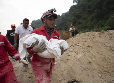A fireman carrying the body of a child recovered from the landslide in Cambray