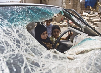 Yemeni girls play in a car damaged by Saudi-led airstrikes in the capital Sana'a