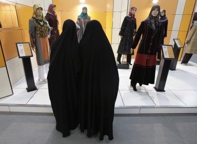 Head-to-toe veiled Iranian women look at mannequins in a women's dress show in Tehran.