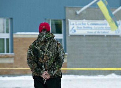 A man holds a rosary as police investigate the scene of a shooting.